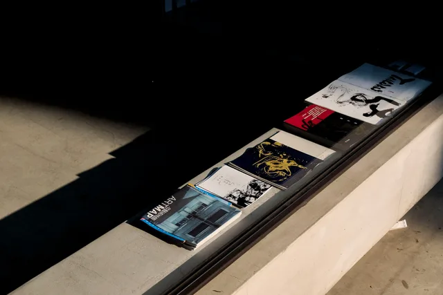 Art magazines and brochures on a sunlit concrete surface, highlighting shadow play and design. Leaflet marketing for local businesses UK still works